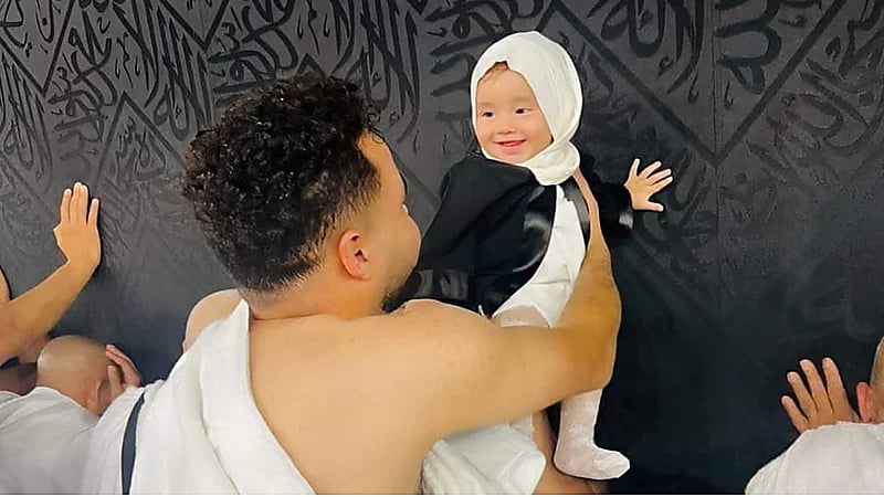 صورة مؤثرة لطفلة رضيعة تبتسم لوالدها أثناء لمسها الكعبة