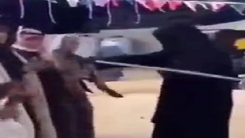 امرأة منقبة تقود مجموعة من الرجال في استعراض رقصة "الدحة"